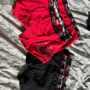 Coca-Cola boxerkalsonger i rött och svart oanvända  -  boxerkalsonger från Coca-Cola. Båda har bred resår med Coca-Cola-logga och tryck på benet. Perfekta för dig som gillar snygga och bekväma underkläder. Oanvända utan förpackning! Strl L 3 röda 2 svarta 5 par sammanlagt. Ordinarie pris: 299 kr. Säljes pga fel storlek!