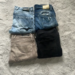 Fyra par jeans i olika färger - Säljer fyra par jeans i olika färger: ljusblå, mörkblå med slitningar, beige och svart. Klassisk femficksmodell med raka ben och normal passform. Perfekta för dig som vill variera din stil med olika färger.