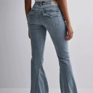 Ljusblå bootcut jeans från True Religion - Säljer ett par ljusblå jeans från True Religion, modell BECCA Mid Rise Bootcut. Jeansen har klassisk femficksdesign, silverfärgade detaljer och en snygg bootcut-passform. Perfekta för dig som gillar en tidlös och avslappnad stil. Storlek 26 men kan användas från storlek 25-27. Köpte för 1300 men har nu insett att denna modell inte passar min kroppsform som jag vill.