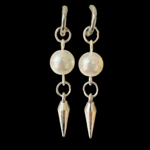 Silverfärgade örhängen med pärldetalj  - Säljer ett par unika örhängen i silverfärg med rund vit pärla och en spetsig, konformad hängande detalj. Perfekta för att ge din stil en cool och modern touch.