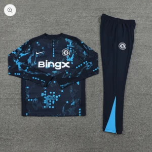 Chelsea träningsset långärmad - Chelsea träningsset med långärmad tröja och byxor. Tröjan är mörkblå med blått och turkost mönster, Chelsea FC-logga och BingX sponsortryck. Byxorna är mörkblå med klubbmärke och ljusblå detalj vid benslut. Perfekt för fotbollsträning.