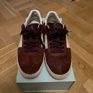 Valentino Flycrews Vinröd - Säljer ett par vinröda Valentino Flycrews. Okej skick, tydliga tecken på användning och en del skavanker. Tappat ett par nitar vilket syns på bilderna 3 och 4. Vissa stygn har lossnat mellan sulan och skon. Hade nog mått bra av en tvätt. Skulle ändå säga att skorna har kvar att ge efter en uppfräschning. Storlek 43