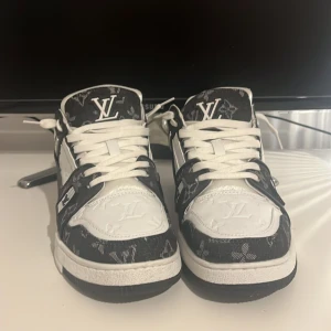 Louis Vuitton sneakers i svart och vitt - Säljer ett par Louis Vuitton sneakers i svart och vitt med klassiskt LV-mönster. Skicket är 10/10 använder aldrig skorna eftersom de inte passar mig.