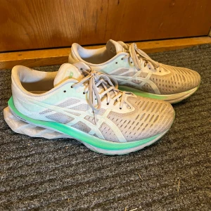 Asics Novablast White/Mint Tint löparskor - Säljer ett par Asics Novablast löparskor i färgen vit och mintgrön. Skorna har ventilerande mesh-ovandel, snörning och en unik, tjock sula för extra dämpning. Perfekta för dig som gillar att springa långt och vill ha en snygg och bekväm sko. Använda under förra sommaren Max 10 pass så enda defekten är färgen.