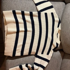 Randig stickad tröja från BikBok - Säljer en vit och marinblå stickad tröja från BikBok med breda horisontella ränder. Tröjan har lång ärm, rund halsringning och ribbade muddar vid ärmslut och nederkant. Perfekt för en stilren och avslappnad look.