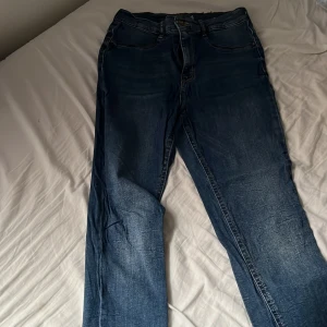 Blå jeansbyxor från Italy - Säljer ett par klassiska blå jeansbyxor från Italy med fem fickor och normal passform. Byxorna har dragkedja och knapp framtill samt bälteshällor. Perfekta till vardags och enkla att matcha med olika toppar.