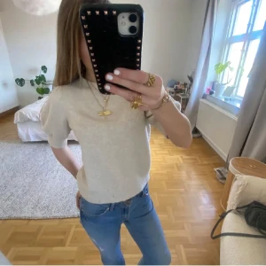 Vit stickad kortärmad tröja - Säljer en söt vit stickad tröja med korta puffärmar och rund hals. Tröjan har en mjuk och mysig känsla och är perfekt att styla med jeans eller kjol. Enkel och stilren design som passar till många tillfällen.