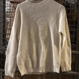 Vit stickad tröja med öppen rygg från RUT&CIRCLE - Säljer en vit stickad tröja från RUT&CIRCLE i storlek S. Tröjan har lång ärm, ribbade muddar och en snygg öppen rygg med djup v-ringning bak. Perfekt för lager-på-lager och en stilren look.