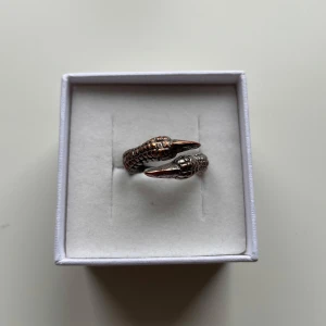 Klo-ring - Cool ring i silverfärgad metall formad som en klo som slingrar sig runt fingret. Detaljerad yta med fjäll-liknande struktur som ger en unik och edgy look. Köpte den på söndagsmarknaden i Frankrike av en urgullig gubbe🥹 Storleken går att justera!
