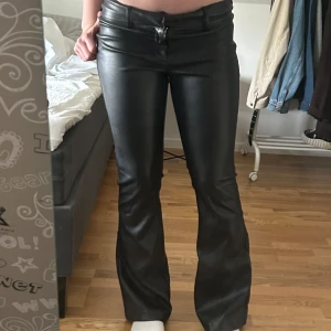 Lågmidjade Svarta skinnbyxor botcut   - Snygga svarta skinnbyxor med bootcut-modell och låg midja. Populära från Gina tricot. Storlek 38. Används endast en gång. 