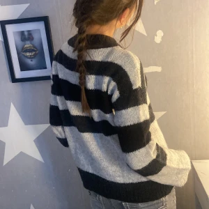 Randig stickad tröja från Vero Moda - Säljer en mysig stickad tröja från Vero Moda i storlek XS. Tröjan har breda svarta och grå ränder, lång ärm och en klassisk rund halsringning. Perfekt för kyliga dagar och enkel att matcha med jeans eller kjol.