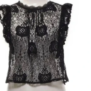 SPETSTOPP ZARA - Säljer en svart, ärmlös blus i spets med volangdetaljer vid axlarna. Blusen har ett vackert spetsmönster och är transparent, perfekt att styla med ett linne under. Rund halsringning och lätt croppad passform.