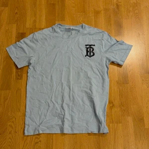 Ljusblå t-shirt från Burberry - Baby blue Burberry t-shirt. Står Burberry London England på ryggen med en Burberry logga på framsidan. 