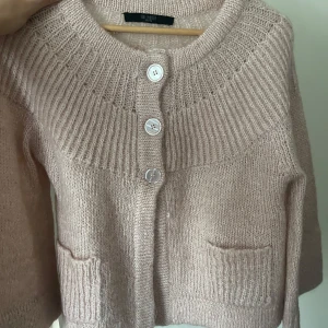 Ljusrosa stickad kofta med knappar från Hallhuber - Superfin ljusrosa stickad kofta med tre stora knappar framtill och två fickor. Koftan har en bred ribbstickad kant vid halsen och är perfekt för våren och sommaren. Mysig och stilren att ha till vardags! Hör av er vid frågor 🥰