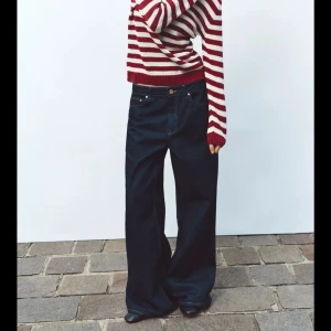 Röd randig stickad tröja  - Säljer ett par mörkblåa jeans med wide passform och normal midja. Jeansen har klassisk femficksdesign och stängs med knapp och dragkedja. Perfekta för en avslappnad och trendig stil.