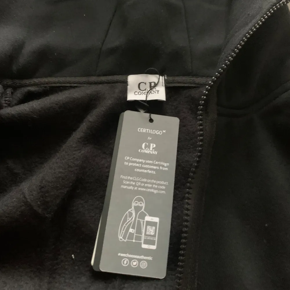 Säljer en svart hoodie från C.P. Company med ikoniska inbyggda glasögon i huvan. Jackan har dragkedja framtill och två fickor med dragkedja. Perfekt för dig som gillar streetwear och vill sticka ut. Storleken känns mer som L lite tight vid armarna. . Hupparit & Collegepaidat.