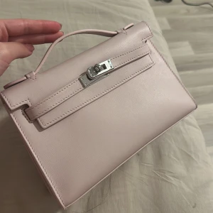 LjusRosa väska i riktig läder med silverdetaljer - Säljer en  ljusrosa/lila handväska i riktig swiftcow läder  med med silverfärgat spänne framtill. Väskan har ett topphandtag.💕