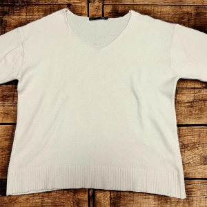 Vit v-ringad stickad tröja från 157 - Säljer en enkel och stilren vit stickad tröja från 157 i storlek S. Tröjan har v-ringning och ribbade muddar vid nederkant och ärmslut. Perfekt för lager-på-lager under kyligare dagar.