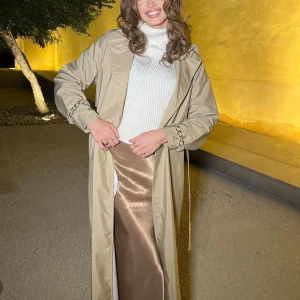 Beige/kamel abaya trenchcoat - Helt ny, fast pris! Inga bud, kommer ej besvara något❌ -inköpt för 1599kr i London, säljs för 850kr  - Referensbilder hur den sitter på Maria Reina😍  - I regnkläds material 🌧️ - Längd 140 cm lång  - Storlek är one size  - Detalj: guld detalj på ärmarna, samt bälte