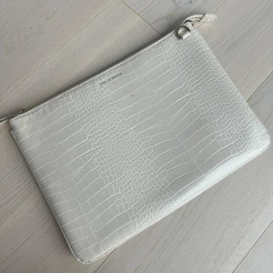Beige dataväska från iDeal of Sweden - Beige dataväska från iDeal of Sweden i krokopräglad syntet. Väskan har dragkedja upptill och stilren design som passar perfekt till att bära det viktigaste. Enkel att matcha med olika outfits.