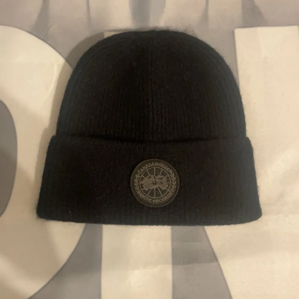 Svart ribbstickad mössa från Napapijri med uppvikt kant och rund logotyp-patch framtill. Perfekt för kalla dagar och enkel att matcha med olika outfits.. Asusteet.