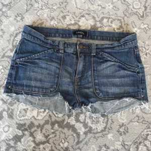 Mörkblå jeansshorts från Lindex - Snygga mörkblå jeansshorts från Lindex med råa, fransiga kanter och klassiska fickor både fram och bak. Shortsen har låg midja och en normal passform, perfekta för varma sommardagar. ⊹ midjemått: 77cm ⊹ jag är 173cm & stl S/36/28 för referens ⊹ läs POLICY (i gillade inlägg) innan köp ⊹ använd gärna ”Köp” ⊹ 