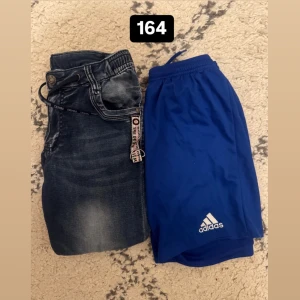 Jeansshorts och blåa träningsshorts från Adidas - Två par shorts: ett par klassiska blå jeansshorts med knapp och dragkedja samt ett par blå träningsshorts från Adidas med vit logga. Perfekta för sommarens aktiviteter.