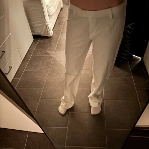 Vita jeans/kostymbyxor med rak passform  - Säljer ett par stilrena vita kostymbyxor med normal passform. Byxorna har raka ben, diskreta fickor och klassisk look. Perfekta för dig som vill ha en clean och fräsch stil. Skriv vid funderingar.