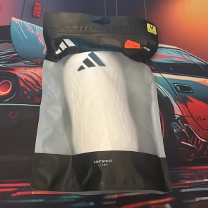 Vit benskydd från Adidas - Säljer ett par vita benskydd från Adidas, modell TIRO SG EU CLUB. De är lätta och har en stilren design med svart Adidas-logga upptill. Perfekta för fotbollsträning eller match. Storlek M (160-175 cm).