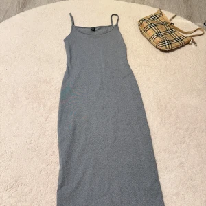 Grå långklänning med smala axelband från SHEIN - Säljer en enkel och stilren grå långklänning från SHEIN. Klänningen har smala axelband och rak passform, perfekt för en avslappnad look. Mjuk och stretchig i materialet för extra komfort.