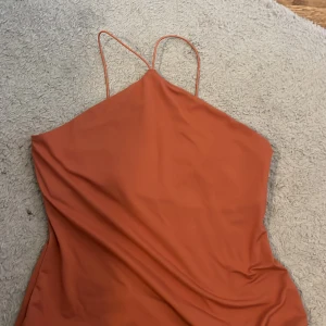 Rostfärgad baddräkt med smala axelband - Säljer en snygg rostfärgad baddräkt med tunna axelband och enkel design. Perfekt för stranden eller poolen. Materialet känns mjukt och följsamt mot kroppen.