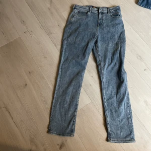 Blå raka jeans från Lee - Säljer ett par klassiska blå jeans från Lee med raka ben och normal passform. Jeansen har fem fickor, gylf med dragkedja och knapp samt Lee-logga på bakfickan och i midjan. Perfekta till vardags och enkla att matcha.