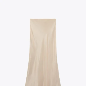 Champagnefärgad långkjol i satin - Elegant långkjol i skimrande champagnefärgad satin. Klänningen har en slank och följsam siluett som ger en lyxig känsla. Perfekt för dig som vill sticka ut med en stilren och tidlös look.