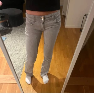 Ljusgrå jeansbyxor med raka ben - Säljer ett par ljusgrå jeansbyxor med normal passform och raka ben. Klassisk femficksmodell med knapp och dragkedja framtill. Perfekta för en stilren och enkel look. sydda lågmidjat. Lite urtvättade