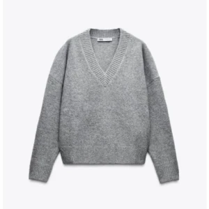 Grå stickad tröja från Zara - Säljer en mysig grå stickad tröja från Zara med v-ringning. Tröjan har långa ärmar och en avslappnad passform, perfekt för kyligare dagar. Den är tillverkad i ett mjukt material som känns skönt mot huden.
