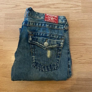 True Religion Jeans Bootcut Flare - !skicka bud för snabb affär! Fina true religion jeans, bootcut. Hålen är design, bra skick. Storlek 27. Mått: Midja 35cm Ytterben 104cm Inneben 80cm Ben öppning 25cm