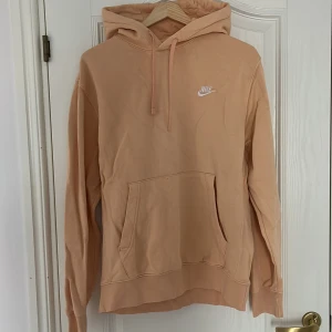 Beige/gul hoodie - Nike - Säljer en snygg hoodie från Nike med klassisk logga på bröstet. Tröjan har huva med dragsko och en stor magficka. Perfekt för nån med en avslappnad stil som samtidigt vill sticka ut och prova nya färger 🌟