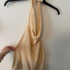 Beige stickad halterneck linnetopp - Säljer en beige stickad halterneck linnetopp med djup urringning i ryggen  och mjuk, luftig känsla. Oklart vilken storlek men passar mig som är XS-S.