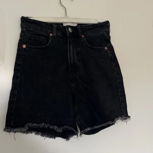 Svarta jeansshorts med fransig kant från H&M - Svarta jeansshorts från H&M med hög midja, använd fåtal gånger fint skick.💕