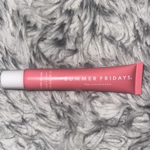 Summer Fridays Lip Butter Balm - Säljer en rosa tub med Summer Fridays Lip Butter Balm. Tuben rymmer 15g och har en vit skruvkork. Perfekt för att återfukta och mjukgöra läpparna med en fräsch känsla. Vegansk formula.