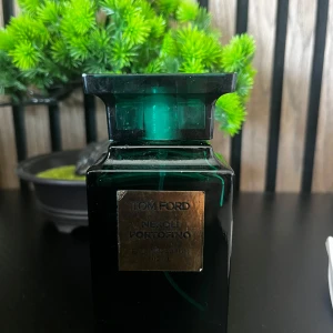 Tom Ford Neroli Portofino Eau de Parfum - Lyxig parfym från Tom Ford i en elegant, mörkgrön glasflaska med guldplakett framtill. Neroli Portofino är en fräsch och citrusdoftande unisexparfym med inslag av neroli, citrus och blommiga noter. Flaskan har en fyrkantig form och exklusiv känsla. Säljer för jag inte gillar den så mycket är inte riktigt min stil har tyvärr inte box för jag tappade bort den när jag flyttade ny pris 2900 mitt pris 2000 pris är inte hugget i stan
