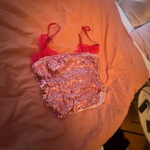 Rosa paljett tubtopp - Säljer en glittrig rosa tubtopp täckt av paljetter. Perfekt för dig som vill sticka ut och glänsa lite extra. Toppen är ärmlös och har en croppad passform.