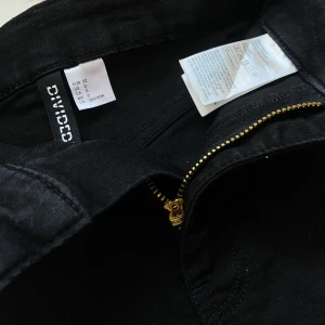 Svarta jeansshorts från Divided - Svarta jeansshorts från Divided med uppvikta benslut. De har dragkedja och knapp framtill och är i storlek 32. Perfekta för sommaren och enkla att matcha med olika toppar. Endast provade, kontakta mig om det finns frågor💞