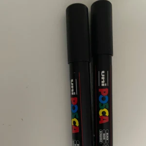 Svarta markers från Uni Posca PC-5M - Två svarta markers från Uni Posca, modell PC-5M. Pennorna har rund spets med bredd 1,8-2,5 mm och är perfekta för både teckning och textning. Färgen är svart och pennorna har svart plasthölje med färgglad logotyp. Endast provade 