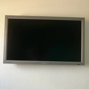 Platt TV från Samsung - Säljer en stilren platt TV från Samsung med silverfärgad ram. TV:n har en rektangulär form och är väggmonterad. Perfekt för vardagsrummet eller sovrummet. Enkel och modern design som passar in i de flesta hem.