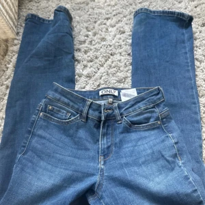 Blå jeans från ONLY - Säljer ett low/midwaist blå jeans från  ONLY. Bra skick i storlek Xxs
