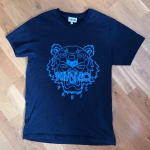 Svart Kenzo Paris t-shirt storlek s - Säljer en svart t-shirt från Kenzo med ikoniskt blått tigertryck och texten 'Kenzo Paris' på bröstet. Pris kan diskuteras.