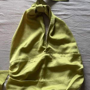 Ljusgrön omlotttopp med halterneck - Säljer en ljusgrön topp med halterneck och omlottdetalj. Topp har knytning i nacken och midjan samt en djup v-ringning framtill. Materialet känns mjukt och har en lätt struktur. Perfekt för sommarens tillfällen!