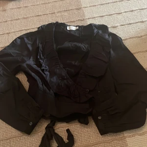 Svart blus - Svart blus från NA-KD Mycket fint skick, aldrig använd Omlott i midjan med knytning Storlek 44 Säljer för 100kr