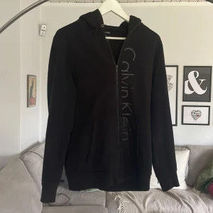 Calvin Klein hoodie stl S - Svart Calvin Klein hoodie med dragkedja i bra skick. Stl S. 